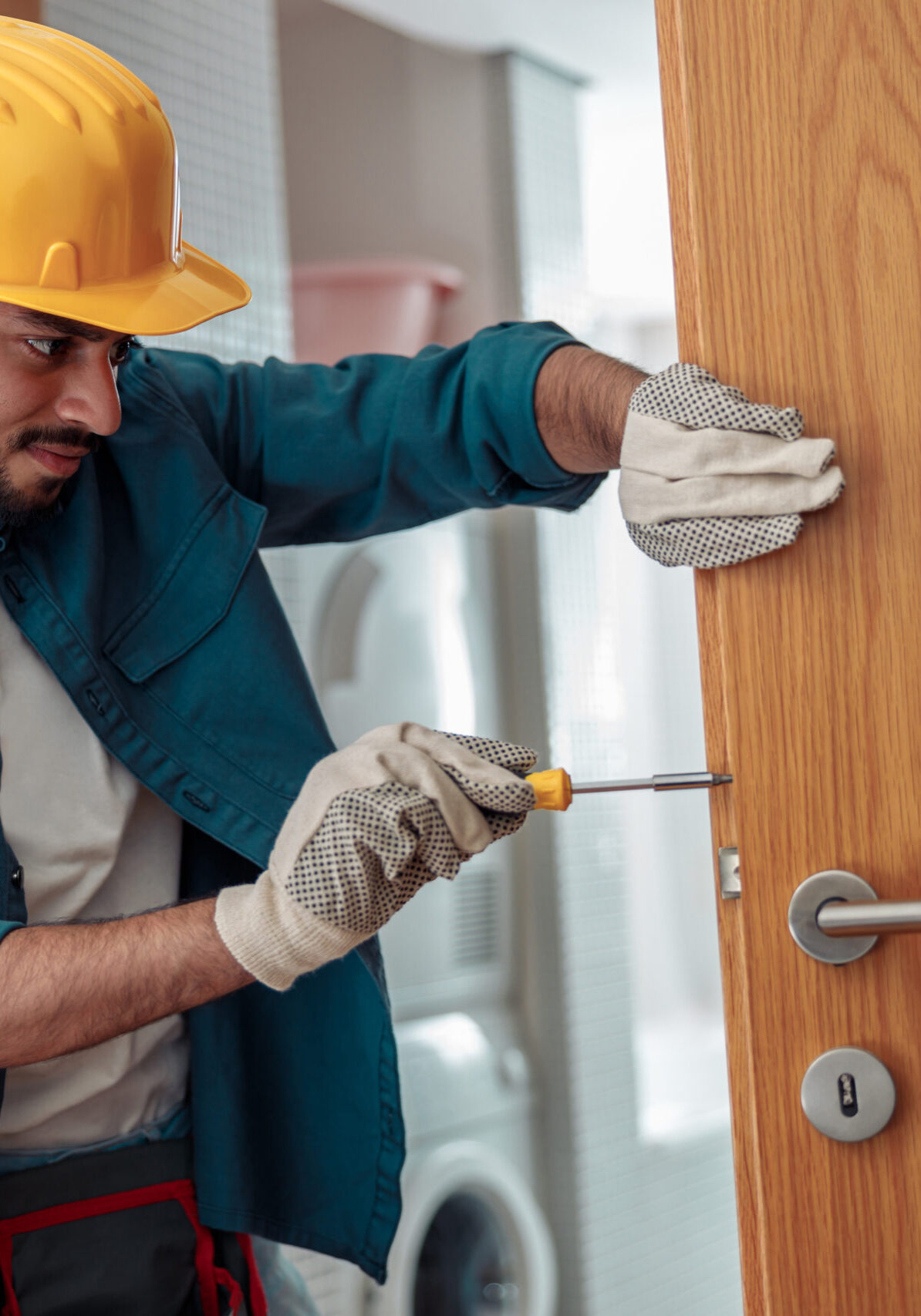 Locksmith workman in uniform installing door knob. Professional repair service. Maintenance Concept